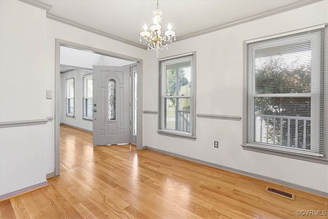 empty room with a notable chandelier, light hardwood / wood-style floors, and crown molding