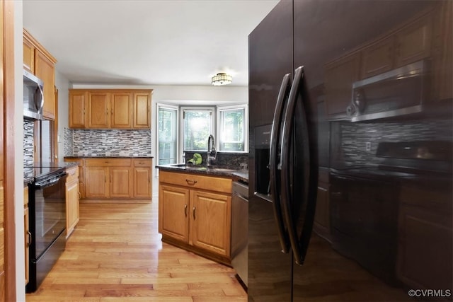 kitchen featuring backsplash, black appliances, light hardwood / wood-style floors, and sink