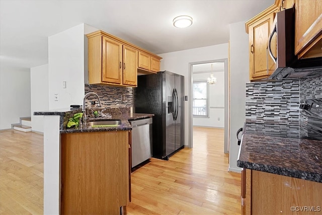 kitchen with backsplash, dark stone countertops, light hardwood / wood-style flooring, and stainless steel appliances