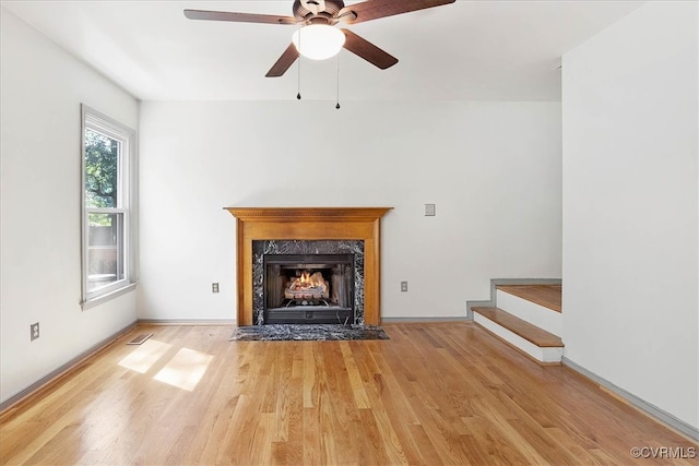 unfurnished living room featuring ceiling fan, light wood-type flooring, and a premium fireplace