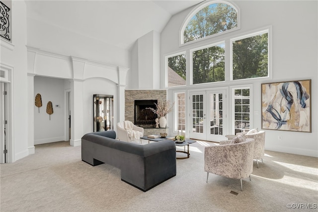 carpeted living room with a stone fireplace, french doors, and high vaulted ceiling