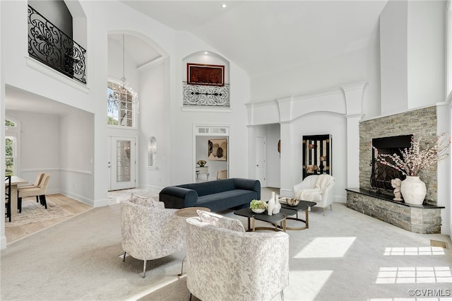 carpeted living room featuring high vaulted ceiling and a stone fireplace