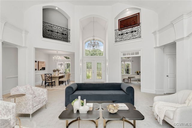 living room featuring french doors, carpet flooring, an inviting chandelier, and a high ceiling