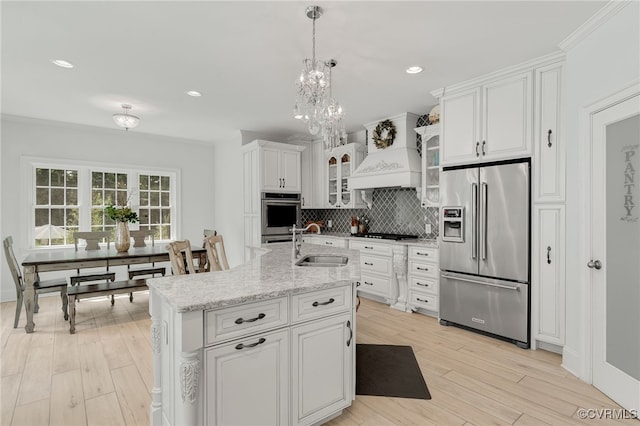 kitchen with appliances with stainless steel finishes, custom range hood, light hardwood / wood-style floors, white cabinets, and sink