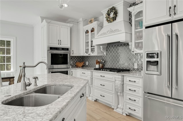 kitchen featuring stainless steel appliances, white cabinetry, light wood-type flooring, and sink