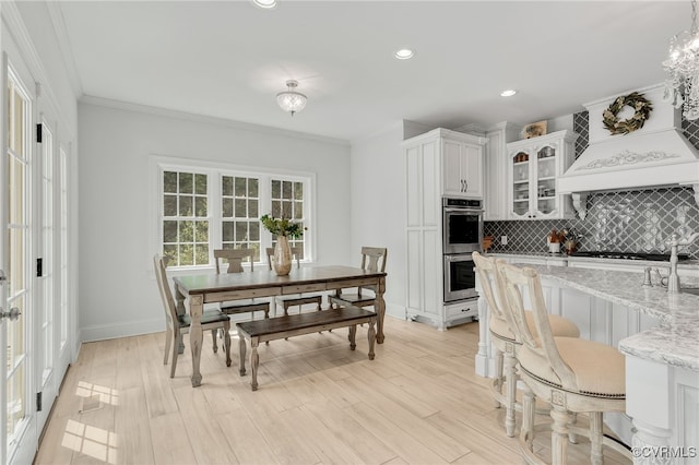 kitchen featuring light hardwood / wood-style floors, light stone counters, white cabinets, stainless steel double oven, and ornamental molding