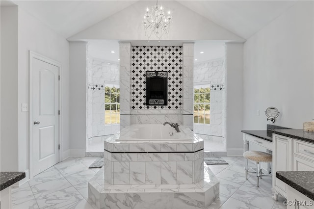 bathroom featuring a notable chandelier, tiled bath, vanity, and a wealth of natural light