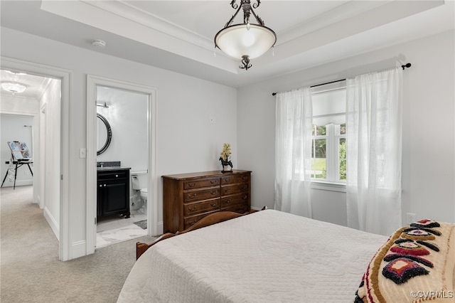 bedroom featuring a raised ceiling, crown molding, light carpet, and ensuite bathroom