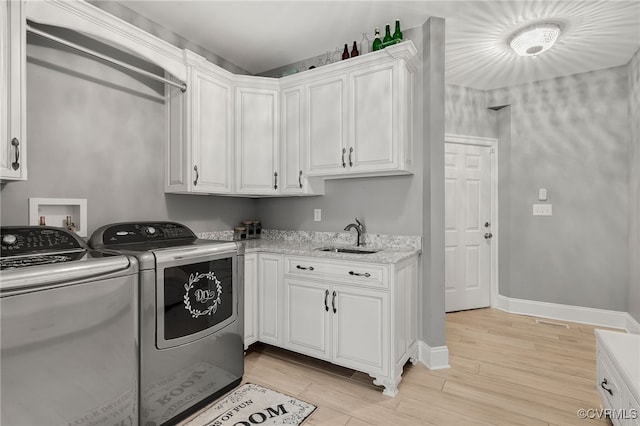 washroom featuring light hardwood / wood-style flooring, cabinets, washer and dryer, and sink