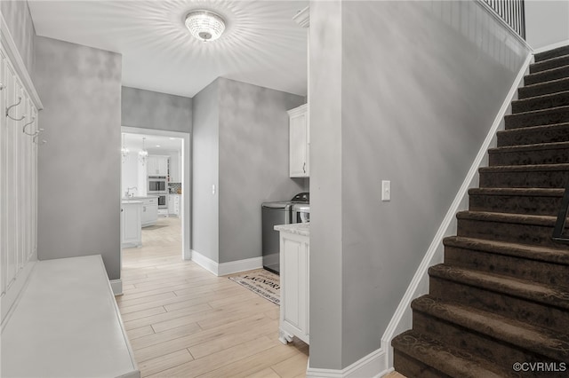 stairs featuring wood-type flooring, washer and dryer, and a chandelier