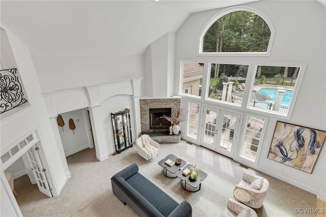 living room featuring high vaulted ceiling, light carpet, and a stone fireplace