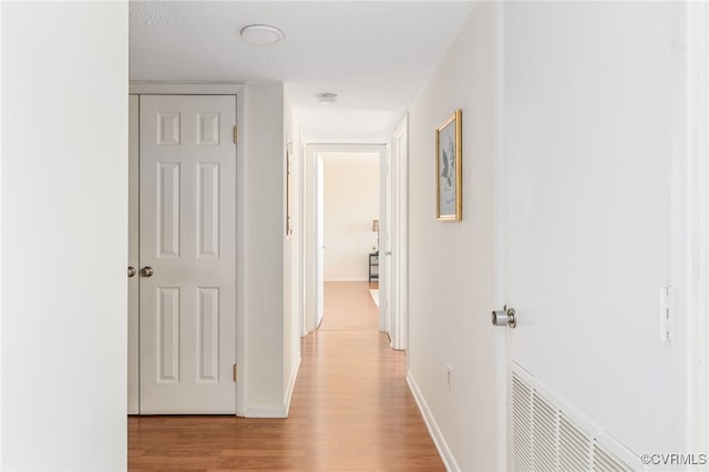 corridor featuring light hardwood / wood-style flooring and a textured ceiling