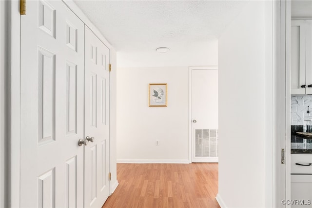 hallway with light hardwood / wood-style floors and a textured ceiling