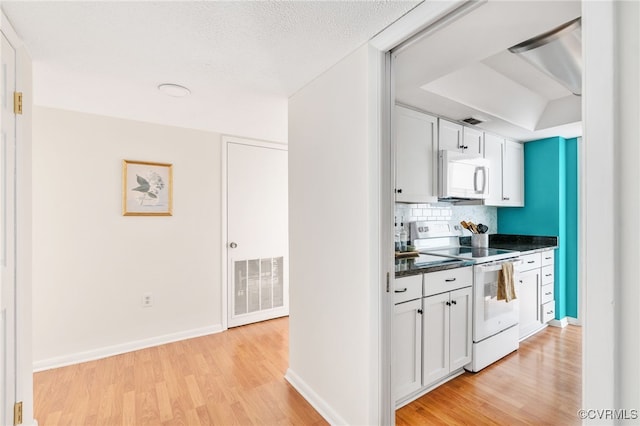 kitchen with a textured ceiling, light hardwood / wood-style flooring, white cabinets, white appliances, and backsplash