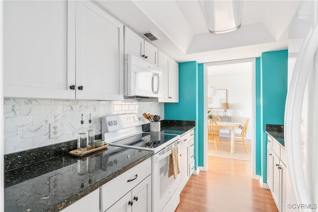 kitchen featuring white appliances, light hardwood / wood-style flooring, white cabinetry, dark stone countertops, and tasteful backsplash