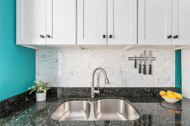 kitchen featuring white cabinetry, sink, decorative backsplash, and dark stone countertops