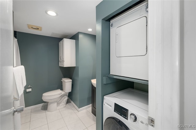 bathroom featuring vanity, stacked washer / drying machine, tile patterned floors, and toilet