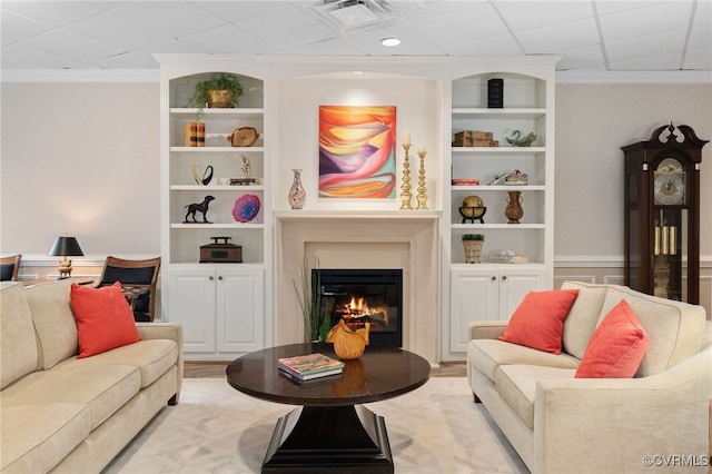 living room featuring built in shelves, ornamental molding, and light wood-type flooring