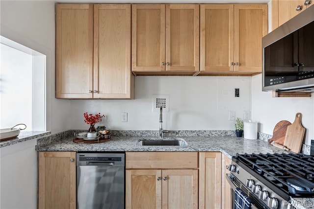 kitchen featuring light stone countertops, appliances with stainless steel finishes, and sink