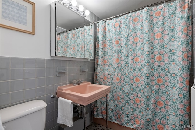 bathroom featuring a shower with shower curtain, toilet, and tile walls