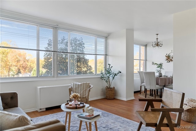 sitting room featuring radiator heating unit, light hardwood / wood-style floors, and a notable chandelier