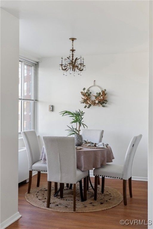 dining space with hardwood / wood-style floors and a notable chandelier