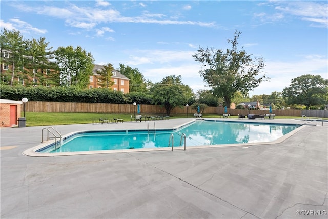 view of pool with a patio and a lawn