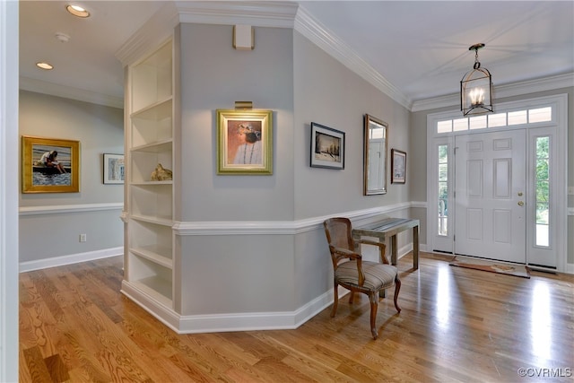 entrance foyer featuring light hardwood / wood-style flooring, crown molding, and a chandelier