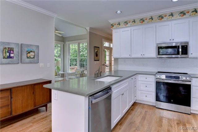 kitchen with stainless steel appliances, white cabinets, kitchen peninsula, and sink