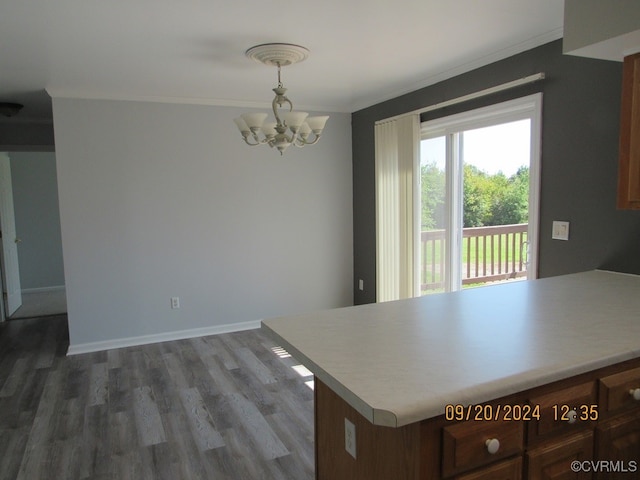 kitchen with a notable chandelier, decorative light fixtures, dark wood-type flooring, and crown molding