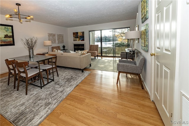 living room featuring a textured ceiling, an inviting chandelier, and light hardwood / wood-style flooring