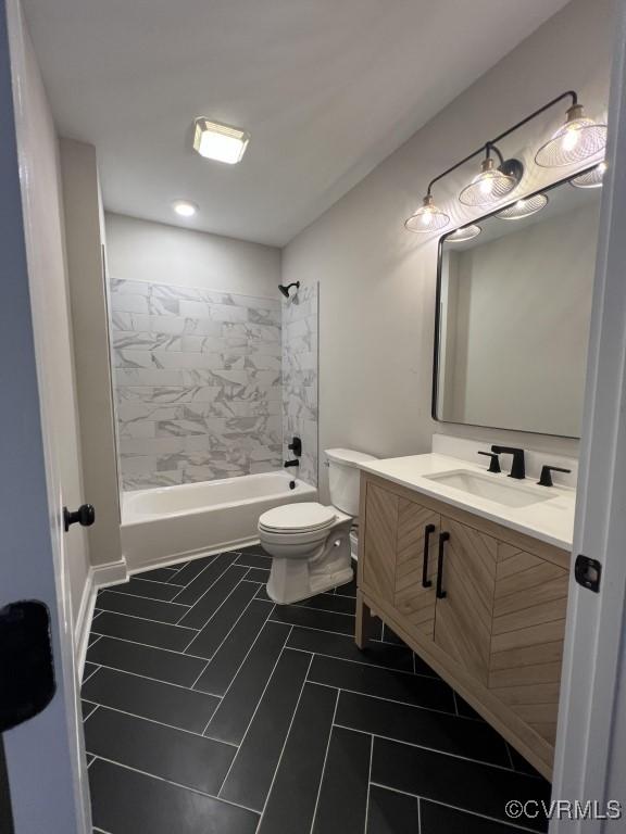 full bathroom featuring tile patterned floors, vanity, tiled shower / bath combo, and toilet