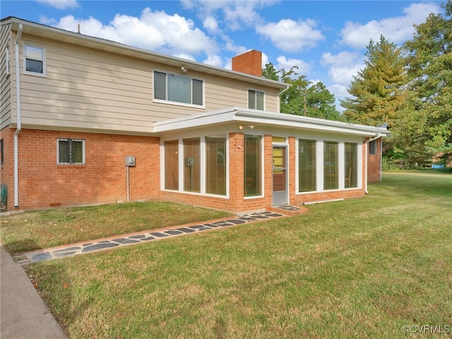 rear view of property with a yard and a sunroom