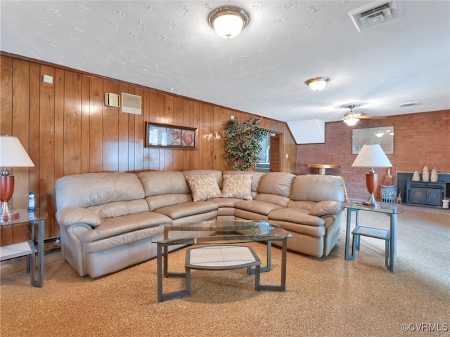 living room featuring wood walls, a textured ceiling, and ceiling fan