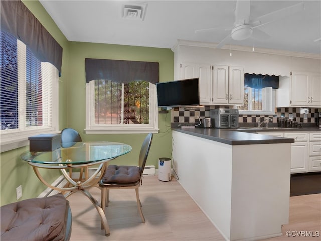 kitchen featuring plenty of natural light, white cabinetry, light hardwood / wood-style flooring, and backsplash