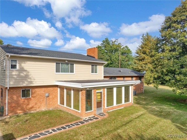 rear view of property featuring a yard and a sunroom