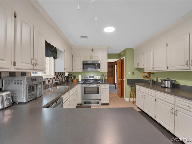 kitchen with white cabinets, ornamental molding, stainless steel appliances, and sink