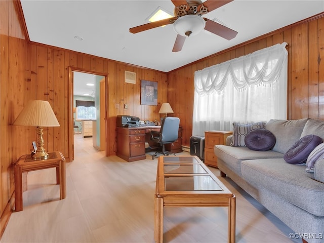 home office featuring ceiling fan, ornamental molding, plenty of natural light, and wood walls