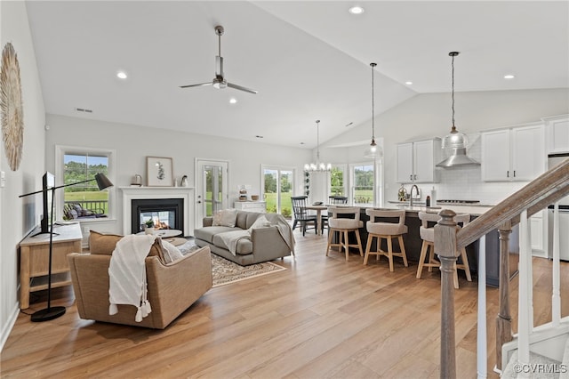 living room with a healthy amount of sunlight, light hardwood / wood-style floors, ceiling fan with notable chandelier, and sink