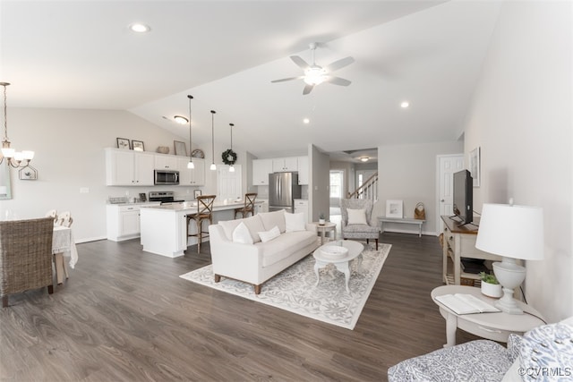 living room with ceiling fan with notable chandelier, lofted ceiling, and dark hardwood / wood-style floors