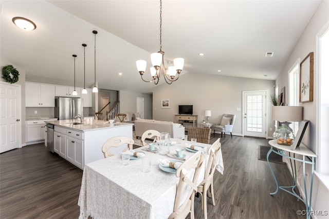 dining space featuring a notable chandelier, sink, dark wood-type flooring, and vaulted ceiling