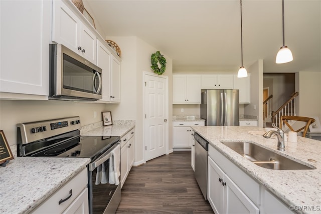 kitchen featuring white cabinetry, dark wood-type flooring, stainless steel appliances, decorative light fixtures, and sink