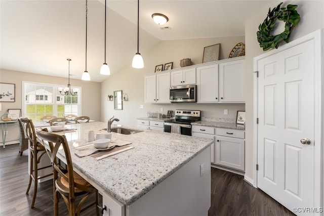 kitchen with white cabinets, decorative light fixtures, appliances with stainless steel finishes, and a kitchen island with sink