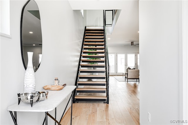 staircase with ceiling fan and hardwood / wood-style flooring