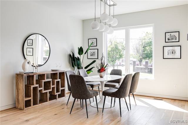 dining space featuring an inviting chandelier, light wood-type flooring, and plenty of natural light