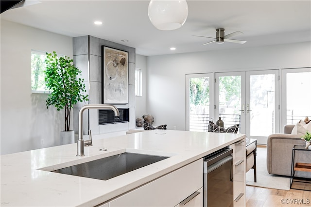 kitchen featuring ceiling fan, light hardwood / wood-style floors, light stone countertops, and sink