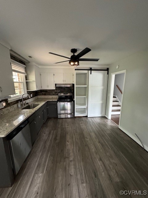 kitchen with white cabinets, sink, stainless steel appliances, dark hardwood / wood-style floors, and a barn door