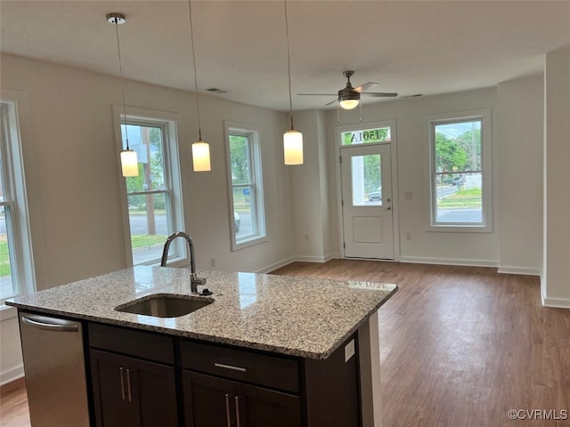 kitchen featuring light hardwood / wood-style floors, light stone counters, ceiling fan, stainless steel dishwasher, and sink