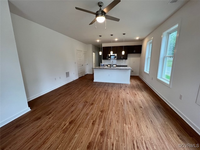 unfurnished living room featuring ceiling fan and dark wood-type flooring