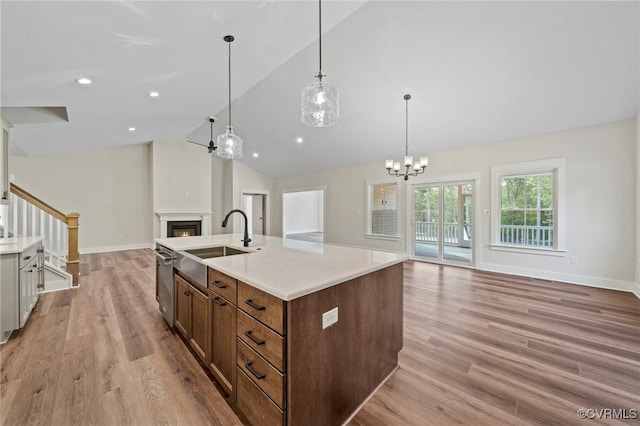 kitchen with hanging light fixtures, high vaulted ceiling, dishwasher, light wood-type flooring, and sink